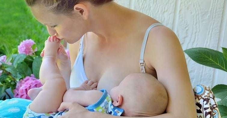 Mother using Luna Lullaby nursing pillow to support baby at breast level