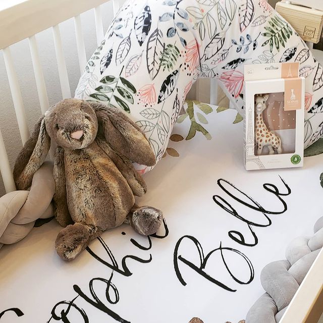 Baby bed filled with gifts and a Modern Leaf Luna Lullaby nursing pillow