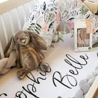 Baby bed filled with gifts and a Modern Leaf Luna Lullaby nursing pillow
